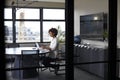 Millennial black businesswoman working alone in an office meeting room, seen through glass wall