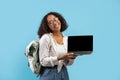 Millennial black female student holding laptop with empty screen for educational website mockup over blue background Royalty Free Stock Photo