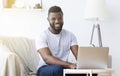 Millennial black man working on laptop in home office