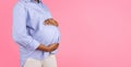 Millennial black pregnant lady touch belly with hands, enjoy motherhood, isolated on pink background Royalty Free Stock Photo