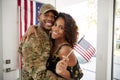 Millennial African American  soldier and wife embracing at home and smiling to camera,waving flag, close up Royalty Free Stock Photo