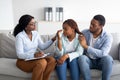 Millennial black woman crying at psychologist's office, loving husband supporting her with professional counsellor Royalty Free Stock Photo