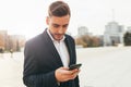 Millennial businessman looks into the screen of his mobile phone. Close-up portrait. Young successful, stylish business man walks Royalty Free Stock Photo