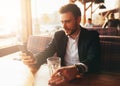 Millennial businessman sitting in a cafe at a table and looking at the screen of his mobile phone. Royalty Free Stock Photo