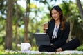 Millennial businesswoman working remotely outside office drinking coffee and using digital tablet Royalty Free Stock Photo
