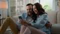 Millennial couple Caucasian man woman married husband wife at home talking using smartphone together happy family Royalty Free Stock Photo