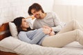 Millennial couple expecting baby, lying on bed and chatting Royalty Free Stock Photo