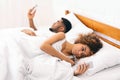 Millennial couple lying on bed back to back with smartphones Royalty Free Stock Photo