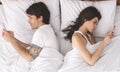 Millennial couple in quarrel, lying in bed back to back, using cellphones Royalty Free Stock Photo