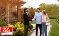 Millennial couple shaking hands with real estate agent near their new house outdoors, copy space Royalty Free Stock Photo