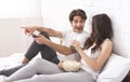 Millennial couple watching movie with popcorn, sitting in bed