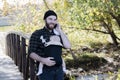 Millennial Dad with Baby in Carrier Outside Talking and Texting