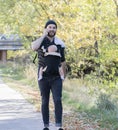 Millennial Dad with Baby in Carrier Outside Talking and Texting