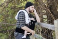 Millennial Dad with Baby in Carrier Outside Talking and Texting
