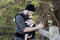 Millennial Dad with Baby in Carrier Outside Talking and Texting