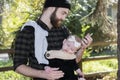 Millennial Dad with Baby in Carrier Outside Talking and Texting