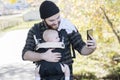 Millennial Dad with Baby in Carrier Outside Walking & Taking Sel Royalty Free Stock Photo