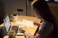 Millennial female employer typing on laptop and signing on docum