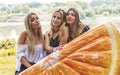 Millennial female friends joke with an orange slice-shaped airbed