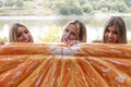 Millennial female friends joke with an orange slice-shaped airbed