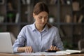 Millennial female social worker counting subsidy rates at office workplace