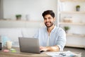 Millennial freelancer. Portrait of happy arab man sitting at desk with laptop, working at home office, copy space Royalty Free Stock Photo