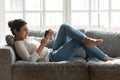 Millennial girl relaxing on couch using cellphone