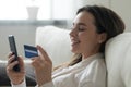 Millennial girl shopping on cellphone using credit card