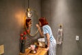 Millennial girl wearing pajamas standing in bathroom applying powder with brush before going out Royalty Free Stock Photo