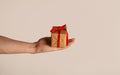 Millennial guy holding wrapped holiday gift on light background, closeup of hand Royalty Free Stock Photo