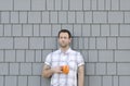 Millennial man holding a coffee mug with a grey neutral background.