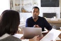 Millennial man with laptop computer giving financial advice to a woman sitting at the table holding a document in her dining room, Royalty Free Stock Photo