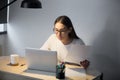 Millennial manager in glasses working on laptop and holding docu