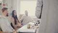 Millennial office workers sit by the table and smile, listening to unrecognisable female team leader giving a speech 4K. Royalty Free Stock Photo