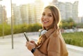 Millennial. Portrait female. Teens looking at camera. Mobile app. Headset phone. Smartwatch. Sunlights rays. Sunset. Winter Royalty Free Stock Photo