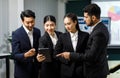 Millennial professional successful female businesswomen holding reading data from tablet screen Asian Indian male businessmen