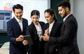 Millennial professional successful female businesswomen holding reading data from tablet screen Asian Indian male businessmen