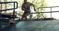 Millennial roller skater jumping high over steps at city skate park.