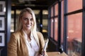 Millennial white blonde businesswoman smiling to camera by the window in an office, close up Royalty Free Stock Photo