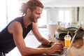 Millennial white man checking fitness app on laptop at home after a workout, side view Royalty Free Stock Photo