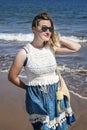 Millennial woman wearing a blue and white paisley dress, a beach bag and sunglasses while enjoying a summer beach vacation Royalty Free Stock Photo