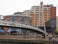 The millennium footbridge in leeds with people drinking at an outside bar after work and men fishing in the river