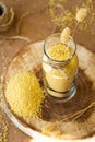 Millet in a glass jar on a wooden stand, next is an ear of wheat