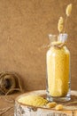 Millet in a glass jar on a wooden stand, next is an ear of wheat