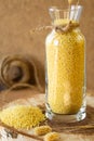 Millet in a glass jar on a wooden stand, next is an ear of wheat