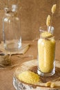 Millet in a glass jar on a wooden stand, next is an ear of wheat