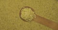 Millet grains in a spoon. Refocusing from a spoonful of grain to a pile of grain. Rotation.