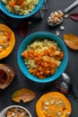 Millet porridge with pumpkin and honey in blue bowls, raw pumpkins and seeds, closeup view