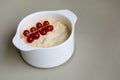 Millet sereal with red currant berries in white bowl on grey background, copy space