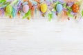 Milticolor bird feathers and Easter eggs decoration. Easter concept. Top view, close up, flat lay on white wooden background Royalty Free Stock Photo